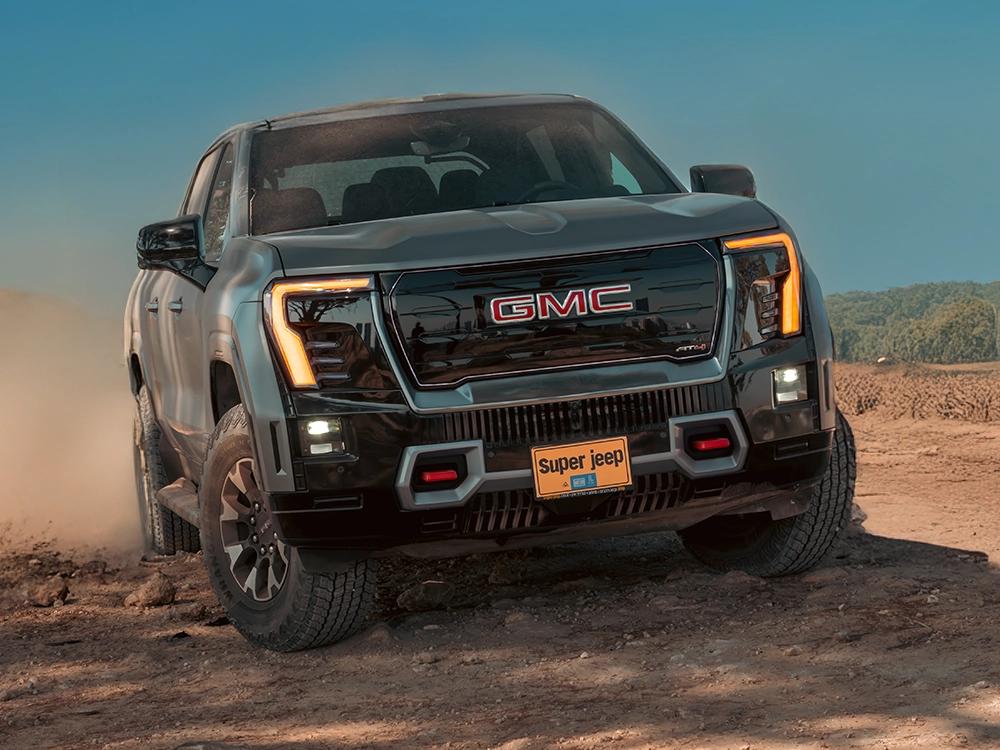 GMC Sierra EV AT4 Max Range 2026 מקדימה בזווית 3/4, טנדר חשמלי מוגבה עם צמיגי שטח 35 אינץ׳ ונוכחות מאסיבית